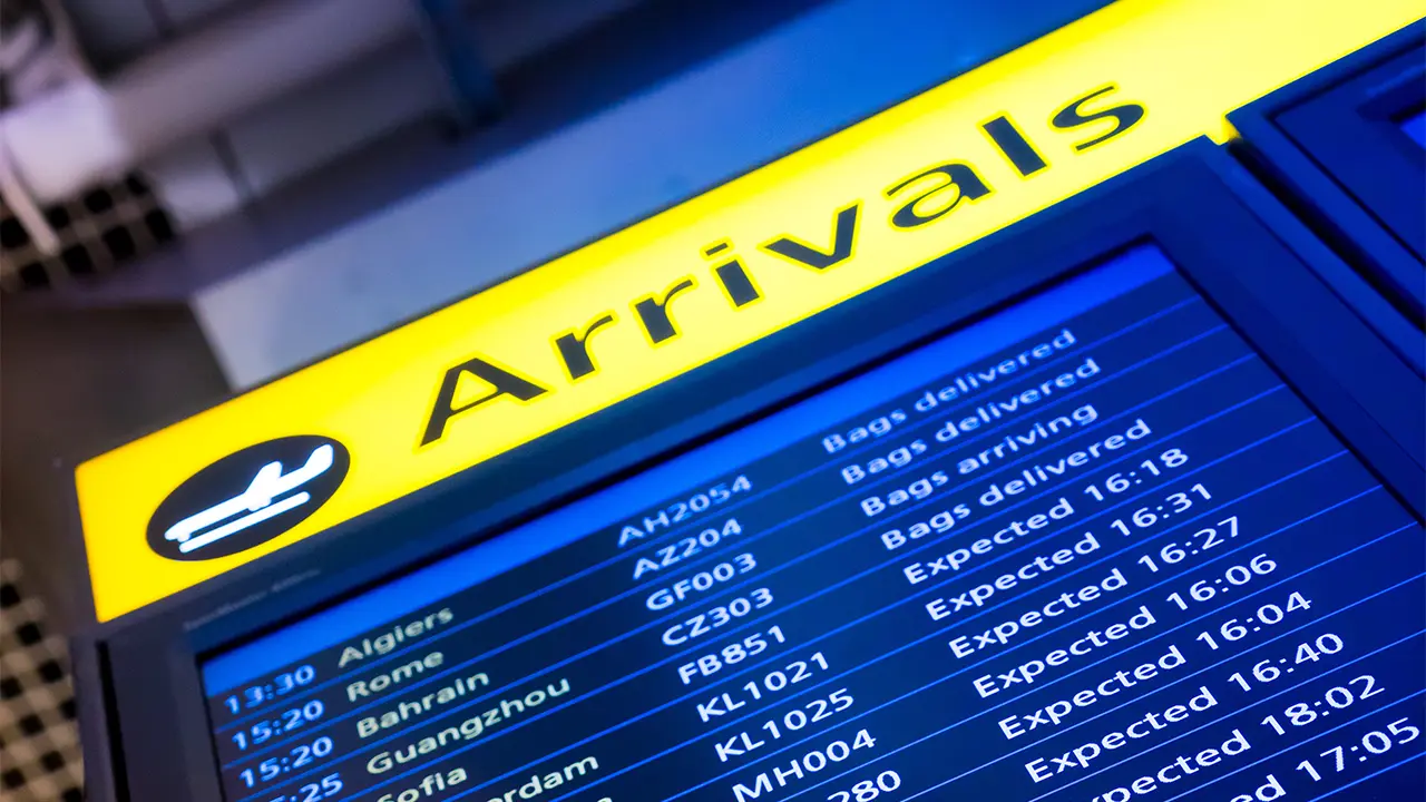 An airport arrivals board showing flight information, illustrating the concept of travel finance.