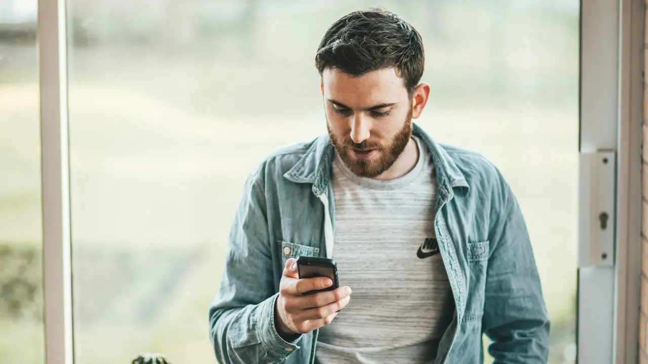 Man checking his smartphone, representing consumer applying for credit using Hope Macy AI decision engine